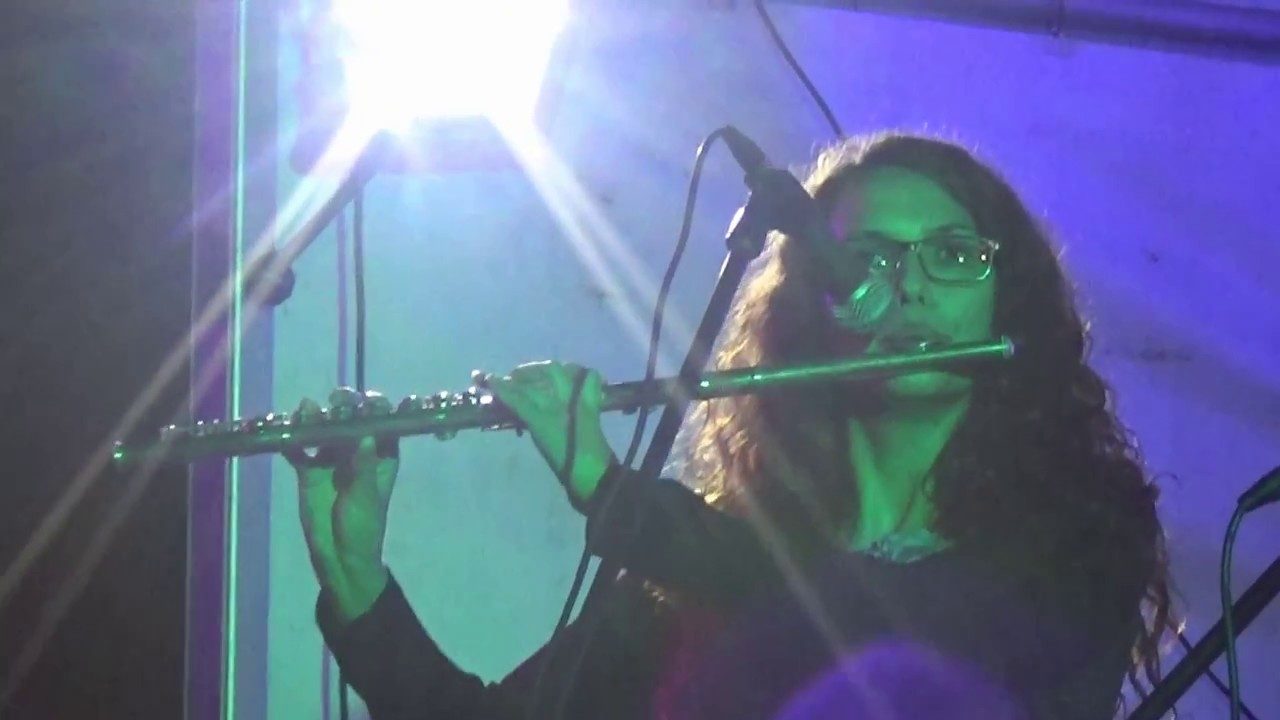 Solistka s flavto v modri luči na koncertu orkestra.